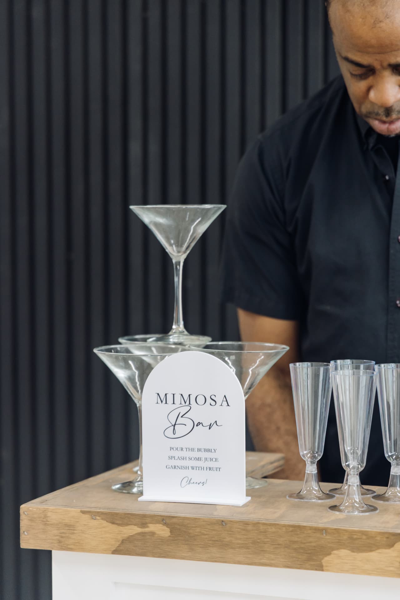 Mimosa bar with a white instruction sign and stacked champagne flutes