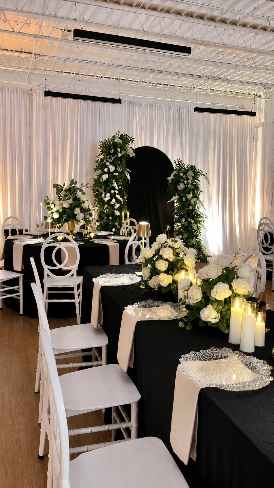 The suite styled with black linens, white chairs, and floral arches