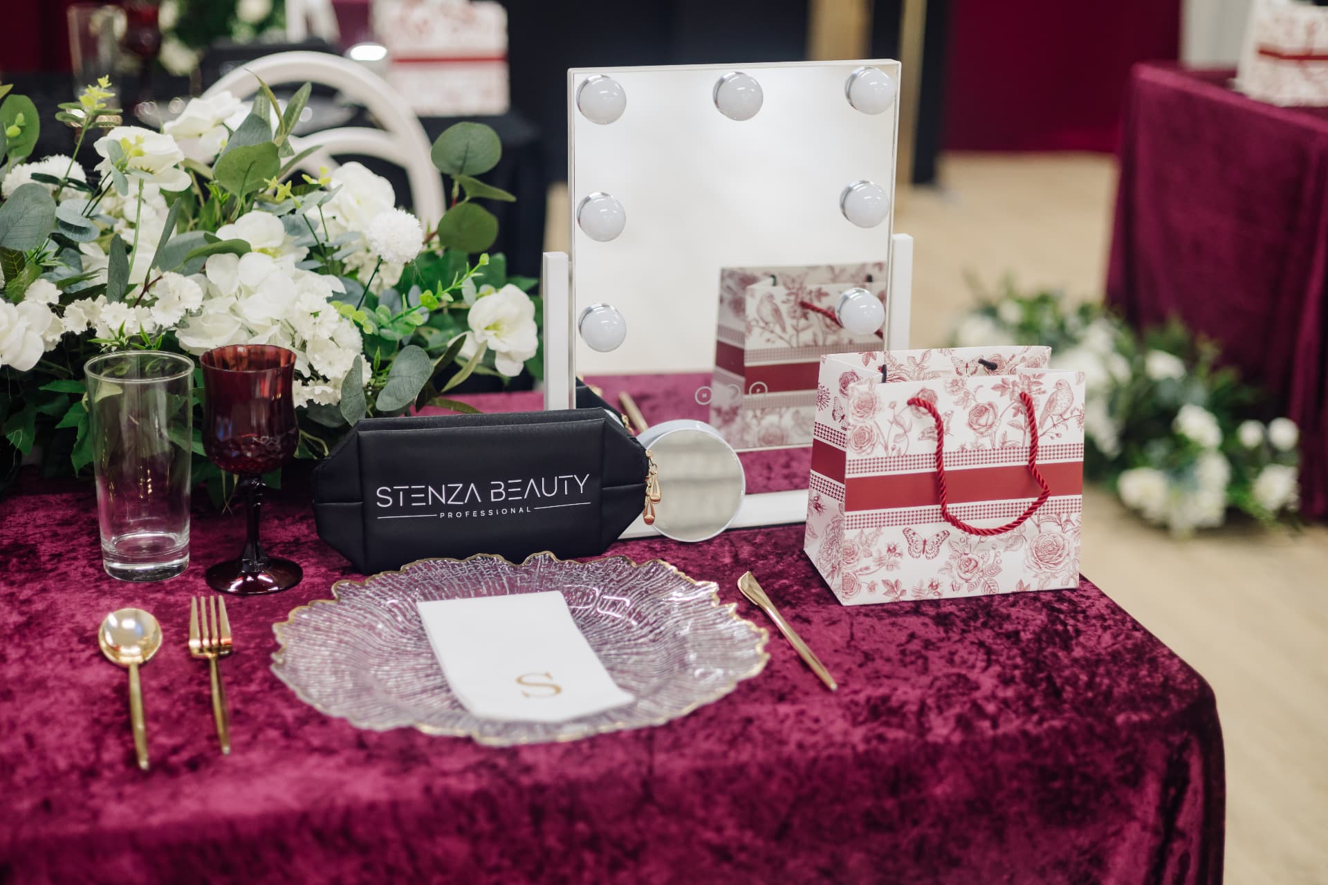 Red velvet tablescape with a monogrammed napkin, gold flatware, and a vanity mirror