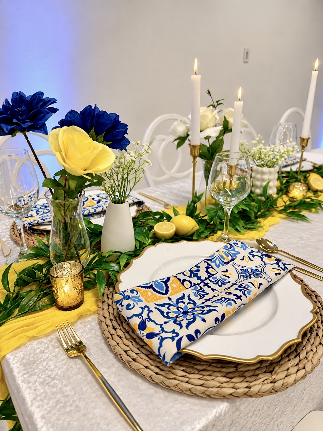 Candlelit blue and yellow dining table set for an evening celebration